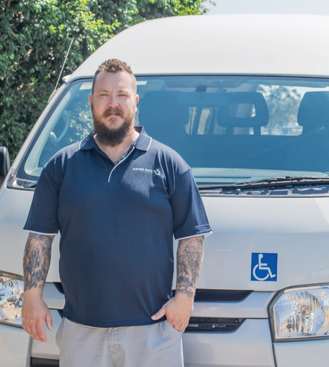 Man in front of a wheelchair-accessible vehicle, ready to assist
