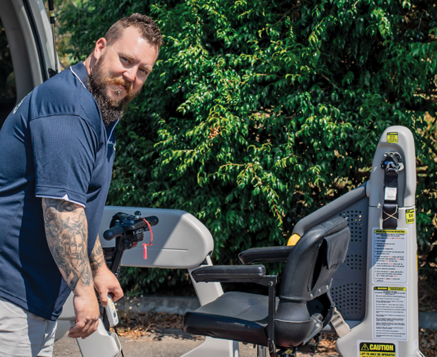 Support worker preparing mobility equipment beside vehicle